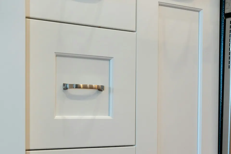 Close-up van een gespoten keukendeur in wit, met een lade en een greep